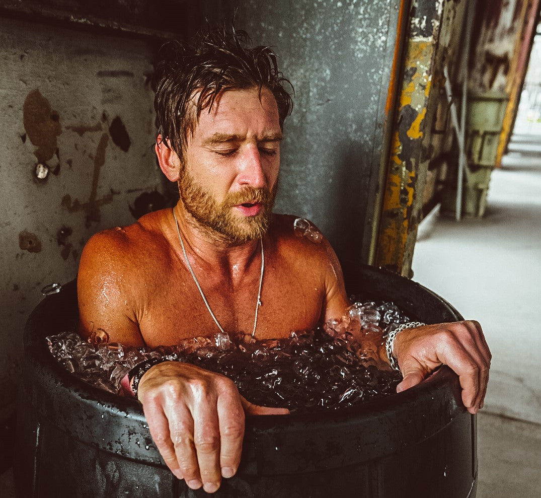 Man in black ice barrel ice bath breathing through a cold therapy session