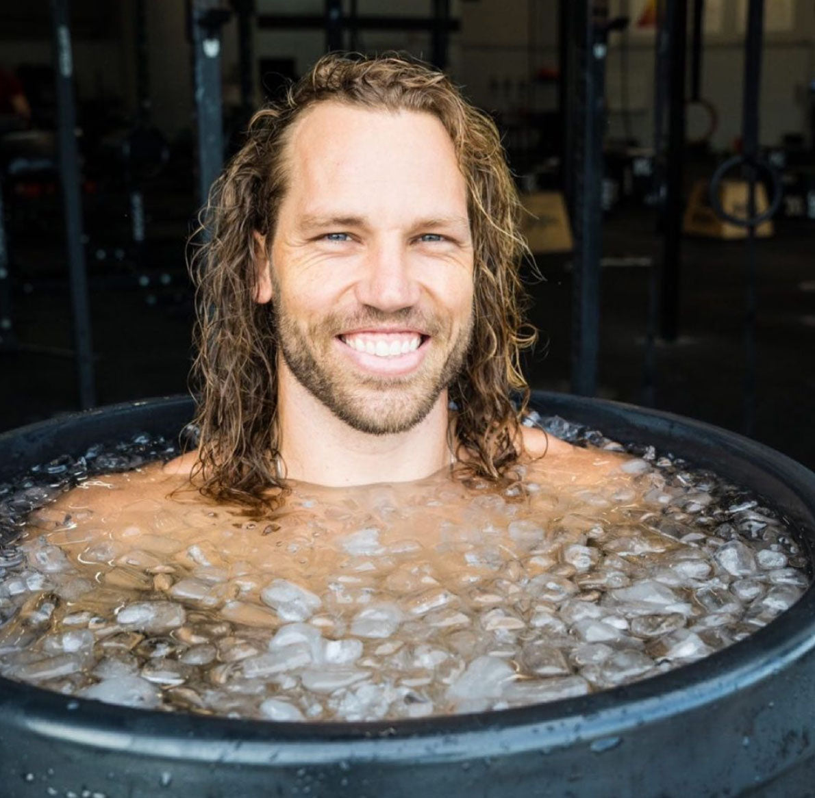 man smiling as he take an ice bath in an ice barrel cold plunge