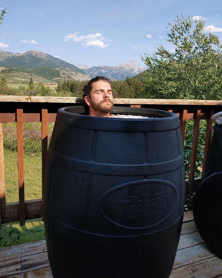Relaxed man taking an ice bath with a mountain view